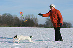 Frau spielt mit Parson Russell Terrier im Schnee