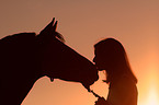 Frau ksst Pferd im Sonnenuntergang